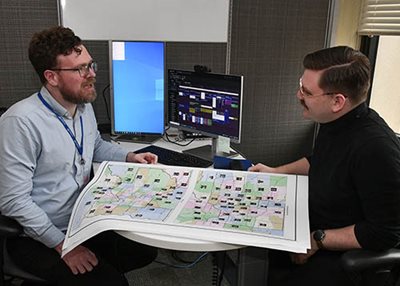 Community relations specialists Michael Sund (left) and Elias Montesa can connect you with Met Council members. Two people sitting at a desk with a map of legislative districts between them.