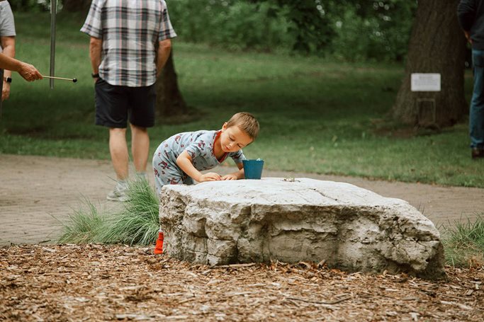 A boy listens to the music coming from a small vase that’s part of a Sound Garden created by James Everest at Silverwood Regional Park in New Brighton. (Photo by Tamar Serin) Boy leans over a vase sitting on a tree stump to hear the recorded sound coming out of it.