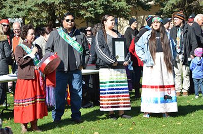 A person speaking into a microphone with many people nearby.