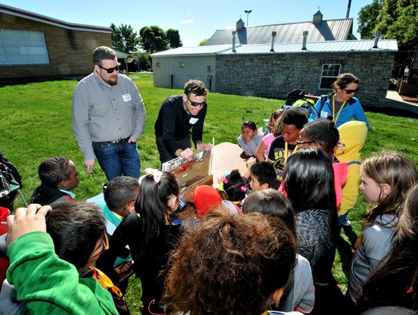 Kids crowding around Environmental Services staffers demonstration