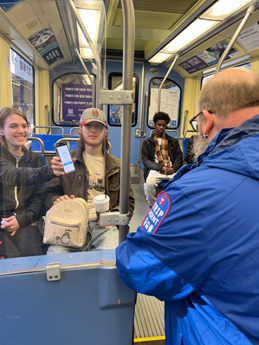 Woman holds up her smart phone to the TRIP agent checking fares on the train car.