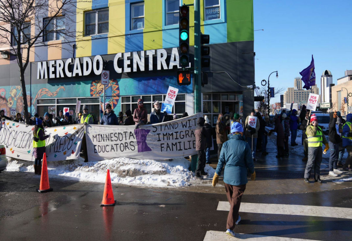 A crowd holding signs in support of immigrant communities is assembled in front of Mercado Central, a business on East Lake Street in Minneapolis