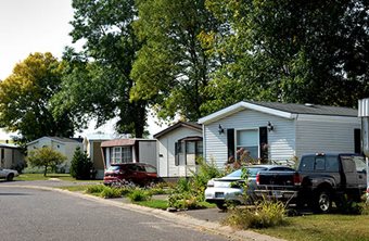 Several large trees provide shade in a mobile home park.