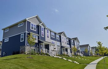A row of townhouses sits on a slight rise above a curved sidewalk.