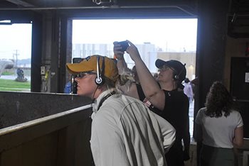 Woman in foreground is peering into the bin, woman in background is taking a photo of the contents.